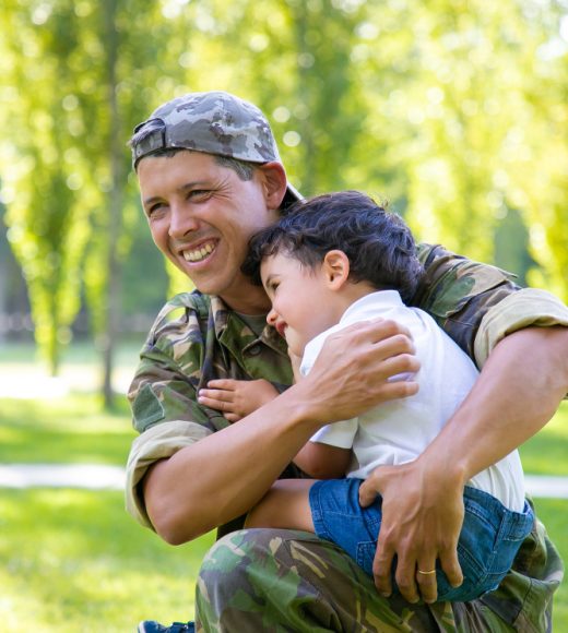 joyful-military-dad-holding-little-son-arms-hugging-boy-outdoors-after-returning-from-mission-trip-vertical-shot-family-reunion-returning-home-concept